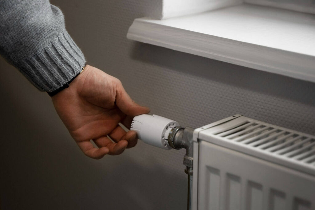 Sistema de calefacción más barato: manos de una persona ajustando un radiador