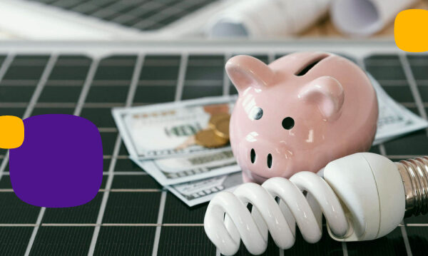 Cómo se desgravan las empresas placas solares: billetes, monedas una bombilla y un cerdito encima de unos paneles solares